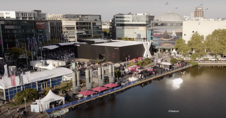 DIGITAL X 2024 Überblick über eine moderne Stadtlandschaft mit Gewässer und Veranstaltungsständen.